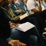 Woman sitting listening to bible teaching with her bible open